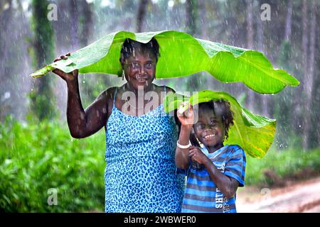 Mutter und Tochter schützen sich vor dem Regen mit einem Regenschirm aus Bananenblättern. Autonome Region Bougainville, Papua-Neuguinea, Asien Stockfoto