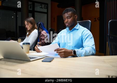 Afroamerikaner mit Kollegen, die im Büro an Laptops arbeiten Stockfoto