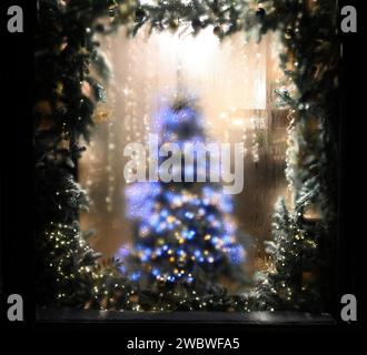 Weihnachtsbaum im Schaufenster. Verschwommener Hintergrund für Weihnachtspostkarte Stockfoto