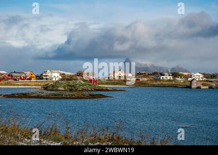 rote und gelbe Häuser am Strand des Atlantik auf der Insel Hillesøya bei Sommarøy, Troms, Norwegen. Landschaft Kalenderfoto mit Bergen im Hintergrund Stockfoto