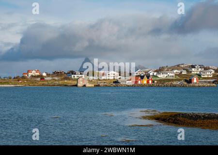 rote und gelbe Häuser am Strand des Atlantik auf der Insel Hillesøya bei Sommarøy, Troms, Norwegen. Landschaft Kalenderfoto mit Bergen im Hintergrund Stockfoto