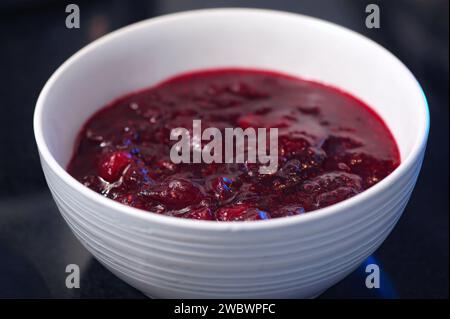 Preiselbeersauce oder Marmelade (Vaccinium macrocarpon) in einer weißen Schüssel mit dunklem Hintergrund. Stockfoto