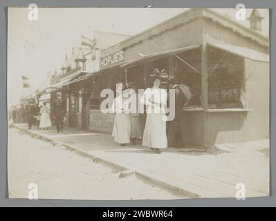 Strandszene mit Spaziergänger auf Planken entlang Ständen, in der Mitte ein Stand von Rademakers Hopjes, Anonym, ca. 1900 - ca. 1910 Foto Niederlande baryta Paper Avenue, Boulevard, Promenade, Esplanade. Strand (als Erholungsort). Stand, Stand ( Markt) Stockfoto