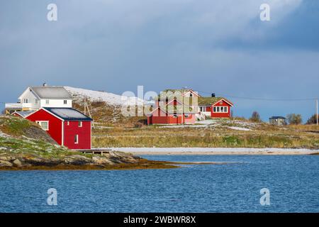 Rotes Haus mit Grasdach am Meer, farbenfrohe Häuser am Ufer des Nordatlantiks. Hölzernes Ferienhaus auf den Inseln Hillesøy Stockfoto