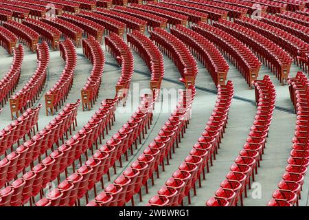 Blick aus einem hohen Winkel über endlose gekrümmte Reihen roter Kunststoffsitze in einem Stadion oder einer Arena, das ansonsten völlig leer ist Stockfoto