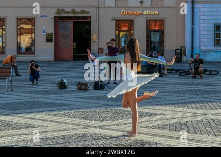 SIBIU, SIEBENBÜRGEN, RUMÄNIEN - 8. JULI 2020: Dämmerungslicht auf dem Großen Platz der Stadt, mit Touristen und einer Ballerina bei der Fotosession. Stockfoto