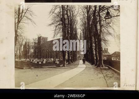 Blick auf den Friedhof und die Kathedrale von Winchester, im Vordergrund eine Avenue, anonym, ca. 1860 - ca. 1870 Foto Teil des englischen Familienalbums mit Fotos von Menschen, Reisen, Cricket und Kunstwerken. Winchester Cathedral Paper. Fotografische Fassade mit Albumenabdruck (von Haus oder Gebäude). Kirche (außen). Friedhof, parkähnliche Grabstätte. Grabstein, Grabstein. Fahrbahn, Gasse. Trees Winchester Cathedral Stockfoto