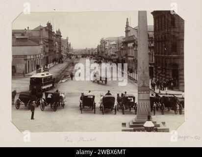 Mainstreet in Port Elizabeth mit Kutschern im Vordergrund an einem Obelisken auf dem Market Square, Anonym, ca. 1880 - ca. 1910 Foto Teil eines Fotoalbums einer Reise durch die Vereinigten Staaten, Honolulu, Niederländisch-Indien, Aden, Sansibar und das südliche Afrika. Port Elizabeth Pappe. Papier. Fotografische Unterstützung der Zugkraft, von Tieren gezogenes Fahrzeug (Kutsche usw.). Straße (+ Stadt (-Landschaft) mit Zahlen, Personal). Obelisk, Needle Port Elizabeth Stockfoto