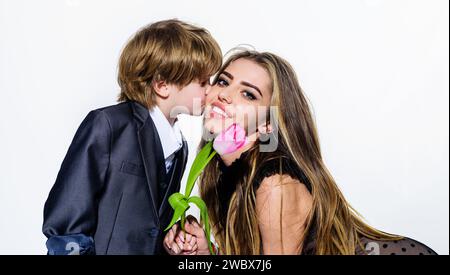 Der süße Bruder gibt Blumen und küsst Schwester. Geburtstagsfeier. Der kleine Junge gibt Tulpe für Mädchen am Valentinstag. Glückliche Frauen oder Mütter Stockfoto