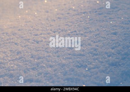 Nahaufnahme von frischem, glänzendem Schnee auf dem Boden an einem sonnigen Tag. Abstrakter Hintergrund der Wintersaison mit geringer Tiefe des Feldes und des Kopierraums. Stockfoto