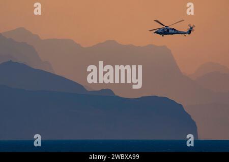 Strait of Hormuz, USA. Dezember 2023. Ein MH-60S Sea Hawk Helikopter der US Navy, der an die „Dusty Dogs“ der Helicopter Sea Combat Squadron 7 angeschlossen ist und vom Flugzeugträger USS Dwight D. Eisenhower der Nimitz-Klasse aus operiert, patrouilliert die Straße von Hormuz am 14. Dezember 2023 im Persischen Golf. Kredit: MC2 Keith Nowak/USA Navy Photo/Alamy Live News Stockfoto