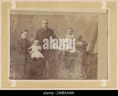 Porträt eines Mannes, einer Frau und zwei Kindern, Bernardus Bruining (zugeschrieben), um 1880 - um 1890 Fotografie. Kabinettfoto Teil des Fotoalbums einer niederländischen Familie mit 168 Cartes de-Visiting- und Kabinettfotos. Arnheim-Karton. Papier. Fotografischer Trägeralbumendruck historischer Personen. studiobedarf  Fotograf. Kleid, Kleid. Kleidung für den oberen Teil des Körpers. Friseurstile - AA -  Frauen. Mantel, umhang. Kleidung, die den ganzen Körper bedeckt. Kind. Kind, Baby  das Alter des Mannes Arnhem Stockfoto