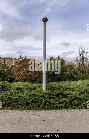 Eine moderne Laternenleuchte zwischen den Hecken eines städtischen Parks Stockfoto