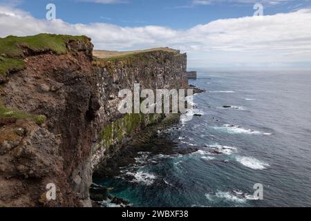 Türkisfarbenes Wasser mit starken Wellen auf steilen, grünen Klippen. Stockfoto