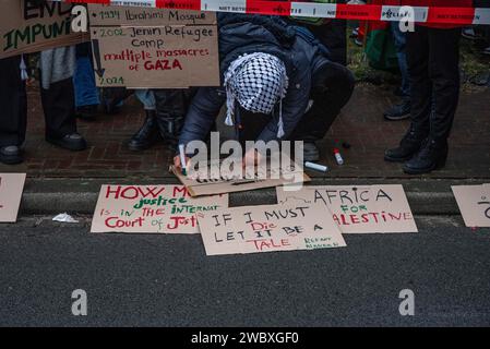 Den Haag, Südholland, Niederlande. Januar 2024. Ein pro-palästinensischer Demonstrant schreibt ein Protestzeichen. Am 12. Januar 2024 demonstrierten pro-israelische und pro-palästinensische Aktivisten vor dem Internationalen Gerichtshof in den Haag. Innerhalb des Gerichtshofs verteidigte sich Israel gegen Südafrikas Anklage des Völkermordes. (Kreditbild: © James Petermeier/ZUMA Press Wire) NUR REDAKTIONELLE VERWENDUNG! Nicht für kommerzielle ZWECKE! Stockfoto