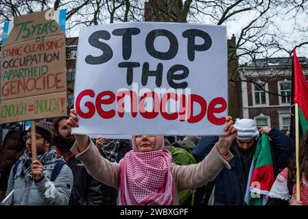 Den Haag, Südholland, Niederlande. Januar 2024. Ein pro-palästinensischer Demonstrant trägt ein Protestschild mit der Aufschrift "Stopp des Genozids". Am 12. Januar 2024 demonstrierten pro-israelische und pro-palästinensische Aktivisten vor dem Internationalen Gerichtshof in den Haag. Innerhalb des Gerichtshofs verteidigte sich Israel gegen Südafrikas Anklage des Völkermordes. (Kreditbild: © James Petermeier/ZUMA Press Wire) NUR REDAKTIONELLE VERWENDUNG! Nicht für kommerzielle ZWECKE! Stockfoto