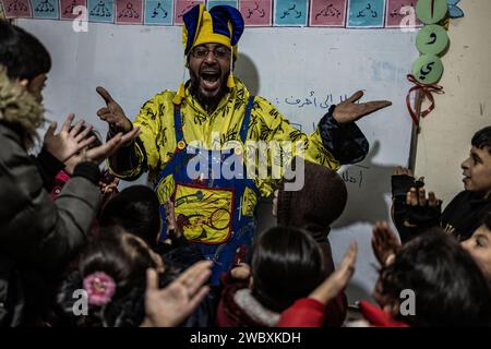 Idlib, Syrien. Januar 2024. Firas Al-Ahmad, als Clown gekleidet, spielt mit Kindern während eines Unterhaltungsprogramms im Rahmen des psychologischen Unterstützungsprogramms für Kinder an der Step of Hope School in Idlib. Die STEP of Hope School für Menschen mit besonderen Bedürfnissen und kriegsverwundete Kinder zielt darauf ab, Kinder mit besonderen Bedürfnissen in die Gesellschaft zu integrieren. Anas Alkharboutli/dpa/Alamy Live News Stockfoto