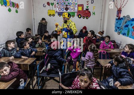 Idlib, Syrien. Januar 2024. Firas Al-Ahmad, als Clown gekleidet, spielt mit Kindern während eines Unterhaltungsprogramms im Rahmen des psychologischen Unterstützungsprogramms für Kinder an der Step of Hope School in Idlib. Die STEP of Hope School für Menschen mit besonderen Bedürfnissen und kriegsverwundete Kinder zielt darauf ab, Kinder mit besonderen Bedürfnissen in die Gesellschaft zu integrieren. Anas Alkharboutli/dpa/Alamy Live News Stockfoto