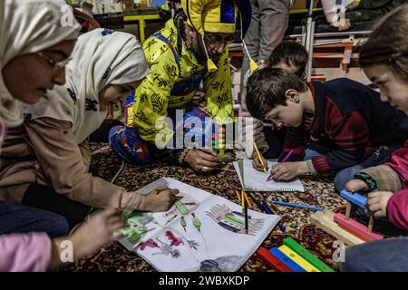 Idlib, Syrien. Januar 2024. Firas Al-Ahmad, als Clown gekleidet, spielt mit Kindern während eines Unterhaltungsprogramms im Rahmen des psychologischen Unterstützungsprogramms für Kinder an der Step of Hope School in Idlib. Die STEP of Hope School für Menschen mit besonderen Bedürfnissen und kriegsverwundete Kinder zielt darauf ab, Kinder mit besonderen Bedürfnissen in die Gesellschaft zu integrieren. Anas Alkharboutli/dpa/Alamy Live News Stockfoto