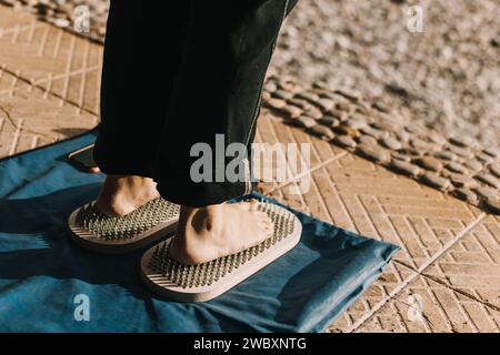 Füße stehen auf einem Sadhu-Brett (Yoga-Brett) mit scharfen Nägeln im Freien. Üben Sie Yoga, Meditation, Konzentration. Stockfoto