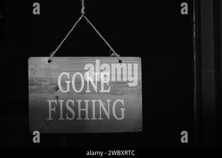 Schwarz-weißes Schild an der Ladentür, das besagt, dass das Geschäft geschlossen ist, weil der Besitzer mit Kopierraum fischen gegangen ist Stockfoto