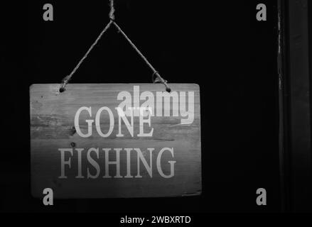 Schwarz-weißes Schild an der Ladentür, das besagt, dass das Geschäft geschlossen ist, weil der Besitzer mit Kopierraum fischen gegangen ist Stockfoto