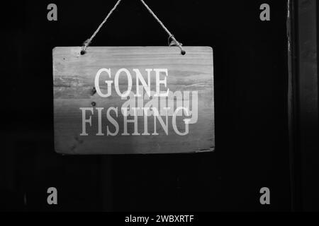 Schwarz-weißes Schild an der Ladentür, das besagt, dass das Geschäft geschlossen ist, weil der Besitzer mit Kopierraum fischen gegangen ist Stockfoto