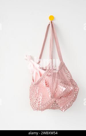 Papierweihnachtsbaum in wiederverwendbarer Mesh-Einkaufstasche, die am Haken hängt. Stockfoto