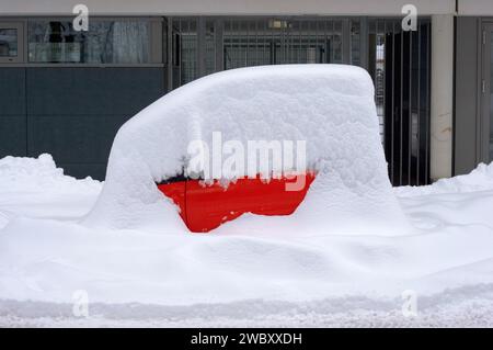 Ein roter Smart, ein winziges Auto, geparkt und komplett mit Schnee bedeckt, Winter, München, Bayern, Deutschland Stockfoto