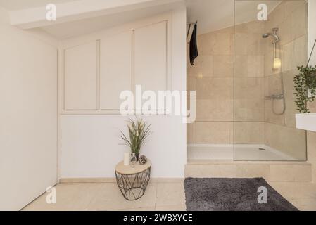 Badezimmer mit weißem Schrank, verglaster Duschkabine und cremefarbenen Marmorfliesen Stockfoto