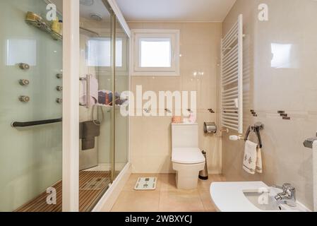 Badezimmer mit Hydromassage-Duschkabine, weißen Porzellantoiletten und weißem Handtuchheizkörper Stockfoto