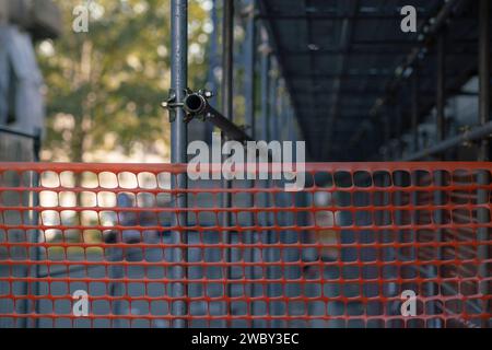 Gut sichtbares Netz, Arbeiten auf einer Baustelle, Zaun einer Baustelle mit gut sichtbaren farbigen Elementen. Weiß, rot und orange Stockfoto