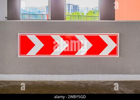 Schild für Umlenkung von Verkehr und Reifen als Hindernisse auf einer Straßenbaustelle. Unter der Brücke befindet sich ein rotes Warnschild auf der Brücke. Weiß und Stockfoto