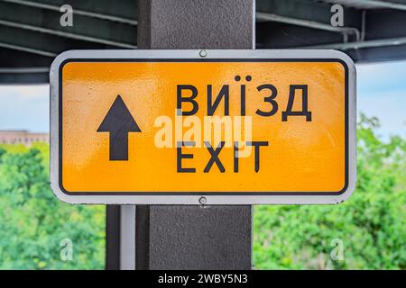 Notausgangsschild in gelbem Brett, das an einer Decke hängt. Ukrainisches Schild: Ausfahrt Stockfoto