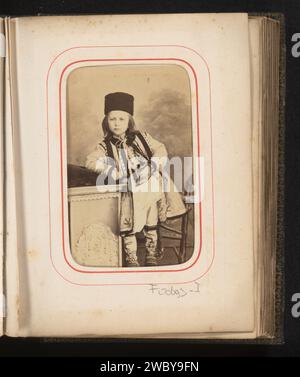 Porträt eines Jungen in rumänischer Tracht, stehend auf einem Stuhl, Carol Popp de Szathmari, 1870 - 1890 Foto. Visitenkarte dieses Foto ist Teil eines Albums. Bukarest-Karton. Fotografischer Trägeralbumendruck historischer Personen. Junge (Kind zwischen Kleinkind und Jugend). Volkstracht, regionale Tracht. Stuhl Stockfoto