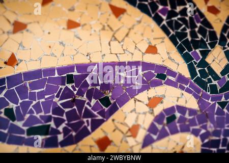 Mehrfarbige Mosaikdetails aus Keramik in Violett, Orange und Gelb. Farbenfroher abstrakter Hintergrund. Architekturdekoration. Mosaikwandfläche. Stockfoto