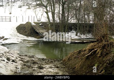 Kreis Arges, Rumänien, ca. 2002. Hölzerne Hängebrücke über den Bach im Winter. Stockfoto