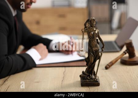 Anwalt arbeitet am Tisch im Büro, konzentriert sich auf die Statue von Lady Justice Stockfoto