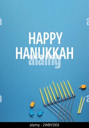 Happy Hanukkah. Menora, Kerzen und Dreidels auf hellblauem Hintergrund, flach Stockfoto