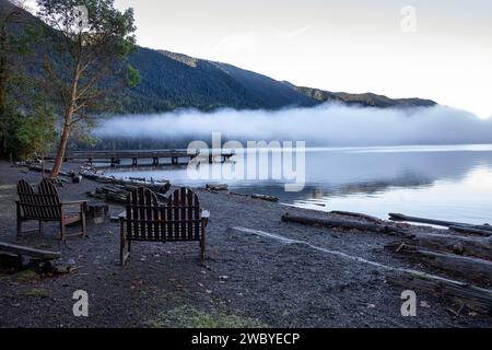 WA23923-00...WASHINGTON - Outdoor Stühle und ein Pier am Ufer des Lake Crescent an einem nebeligen Morgen in der Lake Crescent Lodge. Stockfoto