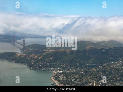 Ein Blick aus der Vogelperspektive auf die Golden Gate Bridge und die umliegende Landschaft, mit einer Nebelschicht, die den Horizont verdeckt. Stockfoto