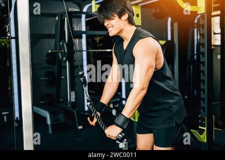 Junger Mann, der Seiltrizeps-Pulldowns durchführt, um Muskeln und Kraft aufzubauen Stockfoto