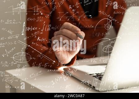 Wissenschafts- und Bildungskonzept. Darstellung der grundlegenden physikalischen und mathematischen Formeln und Mann, der am Laptop arbeitet, am Tisch, Nahaufnahme Stockfoto