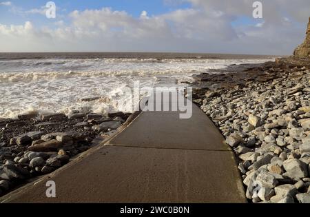 Die Betonstartrampe und der Zugang zum Southerndown Beach mit der Flut auf dem Weg in einen kalten, aber sonnigen Wintertag. Stockfoto