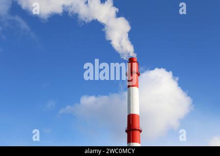 Fabrikschornstein auf blauem Himmel und Wolkenhintergrund mit weißem Rauch. Konzept der Dampfanlage, Luftverschmutzung, Heizsaison Stockfoto