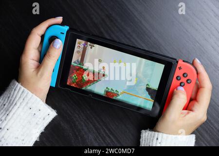 Mädchen spielt Super Mario Bros Wunderspiel auf der Nintendo Switch-Konsole im Handheld-Modus Stockfoto