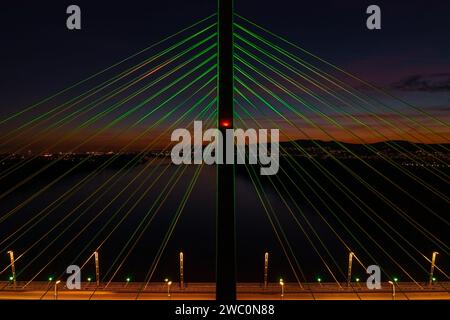 Aus nächster Nähe sehen Sie die beleuchtete Megyeri-Brücke in einer seltenen weihnachtsdekoration. Buda Hügel im Hintergrund. Stockfoto