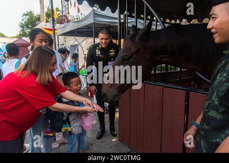 Bangkok, Thailand. Januar 2024. Kinder, die während des Thailändischen Kindertages auf einer Basis der Royal Thai Army in Bangkok beim Füttern eines Pferdes gesehen wurden. Quelle: SOPA Images Limited/Alamy Live News Stockfoto