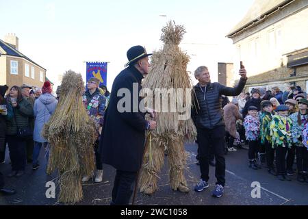 Der Strohbär wird während des Whittlesea Straw Bear Festivals in Whittlesea, Cambridgeshire, begleitet von Pflegern, Musikern und Tänzern durch die Straßen geführt. Bilddatum: Samstag, 13. Januar 2024. Stockfoto