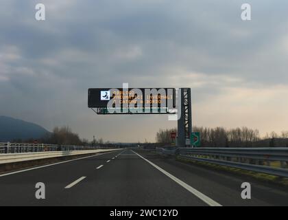 Portaltor mit Autobahnschild, das darauf hinweist, dass Schneeketten vorgeschrieben sind und dass es in Italien eine automatische Geschwindigkeitsüberwachung gibt Stockfoto